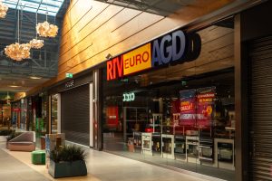 RTV Euro AGD como un hombre calvo con el flequillo en el borde de la mesa. Una exhibición extraña en la tienda.